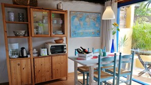 Una cuina amb armaris de fusta, microones, cafetera i una taula de dinar amb cadires.