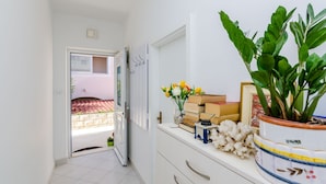 A hallway with a sliding door leading to an outdoor area, a potted plant, and a small table with books and decorative items. - Pension Matusic - Comfort double room (Dubrovnik)