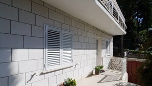 A building facade with white exterior walls, two windows with white shutters, and a small balcony area with potted plants. - Pension Matusic - Comfort double room (Dubrovnik)