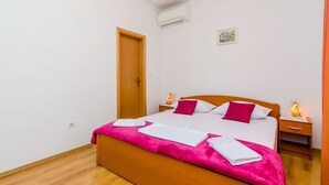 A bedroom with a wooden bed, white bedding, and pink accents. - Pension Matusic - Comfort double room (Dubrovnik)