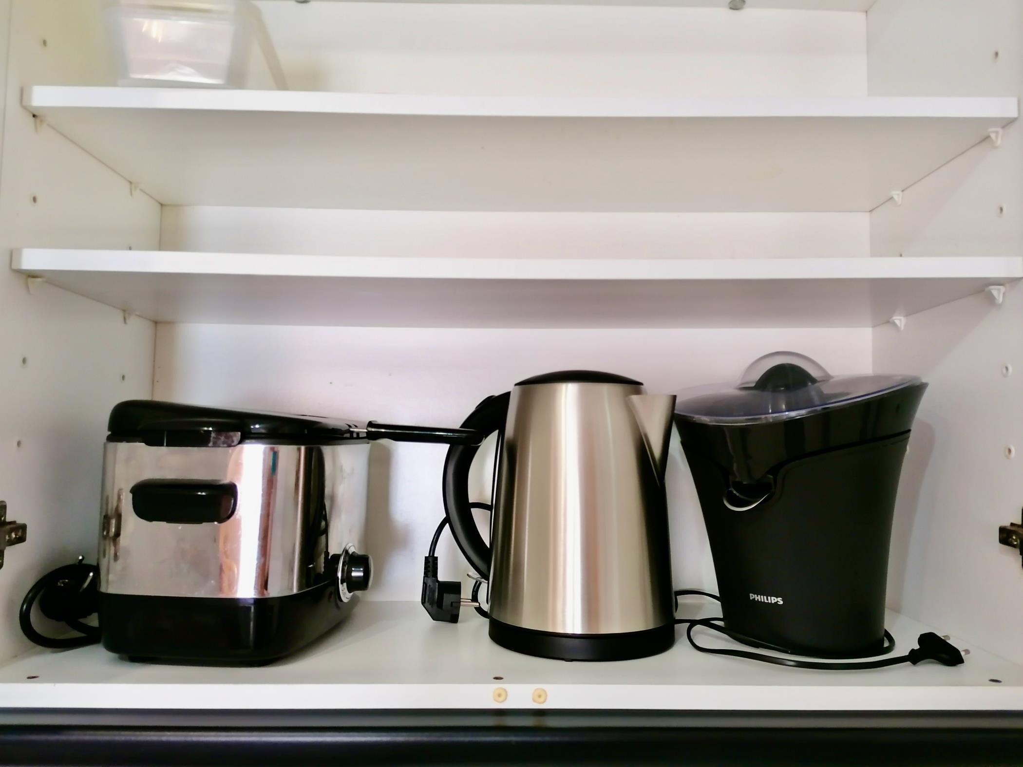 Une étagère de cuisine avec une machine à café, une bouilloire et un récipient.
