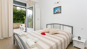 A bedroom with a bed, a nightstand, a window with curtains, and a view of the outdoors. - Studios IM - Studio Apartment with Shared Terrace (A1) (Dubrovnik)