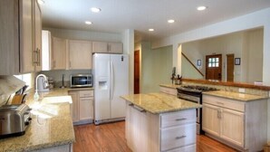 A modern kitchen with granite countertops, a refrigerator, microwave, stove, and white cabinetry. - Scenic Wonders Alder Lodge 3 Bedrooms (Yosemite National Park)