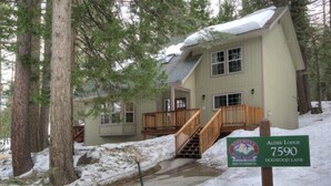 A lodge with a wooden staircase leading to a porch, surrounded by snow and trees. - Scenic Wonders Alder Lodge 3 Bedrooms (Yosemite National Park)