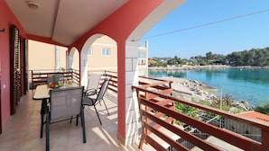 Un balcone con tavolo e sedie, vista su un corso d'acqua e sulla costa.