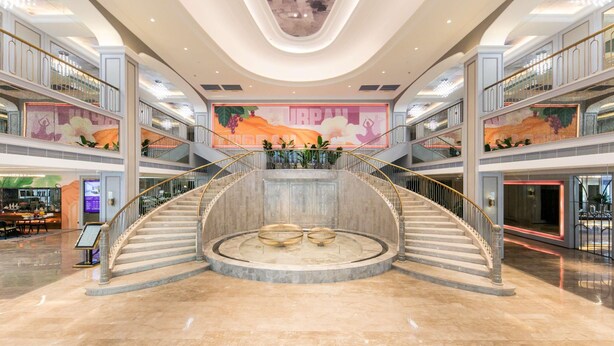 A spacious atrium with a central spiral staircase, multiple levels, and a large mural on the walls. - Mercure Turpan Downtown (Turpan)