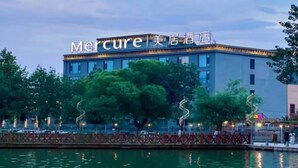 A hotel with a modern design, a signboard with the name 'Mercure,' and a waterfront view. - Mercure Turpan Downtown (Turpan)