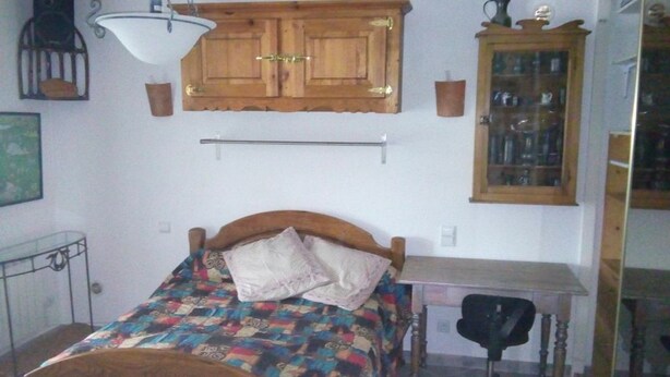 A bedroom with a wooden bed, a desk, a chair, a cabinet, and a hanging light fixture. - 2 bedrooms in a pullhouse and jacuzzi (Ventiseri)