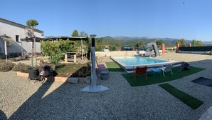 Un jardin avec une piscine, du mobilier d’extérieur et une pergola.