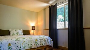Ein Schlafzimmer mit einem Bett, einer Nachttischlampe und einem Fenster mit Vorhängen.