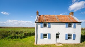 Une maison blanche avec des volets bleus, un toit en tuiles et une porte.