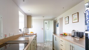 Une cuisine moderne dotée d’un îlot central, d’une cabine de douche en verre et d’un réfrigérateur aux motifs bleus et blancs.