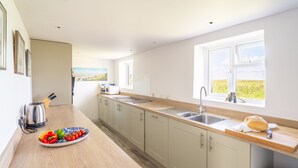 Une cuisine moderne avec un plan de travail en bois, un évier et une vue sur la campagne.