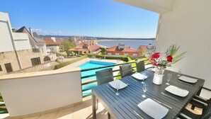 Un balcon avec une table dressée pour le dîner, donnant sur une piscine et une plage.