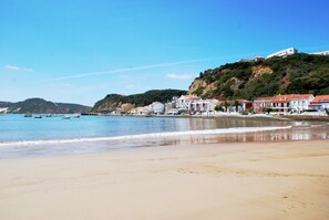 A coastal town with buildings along the beach and boats in the water.