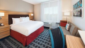 A hotel room with a large bed, a desk, a chair, a nightstand, a lamp, and a window with sheer curtains. - TownePlace Suites by Marriott Atlanta Lawrenceville (Lawrenceville)