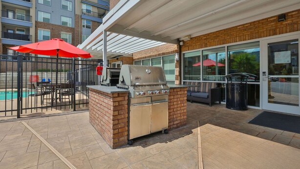 An outdoor patio with a barbecue grill, seating area, and a pool in the background. - TownePlace Suites by Marriott Atlanta Lawrenceville (Lawrenceville)