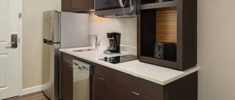 A modern kitchen with stainless steel appliances, a dishwasher, a coffee maker, and wooden cabinetry.
