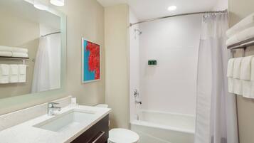 A modern bathroom with a large mirror, a bathtub, and a shower.