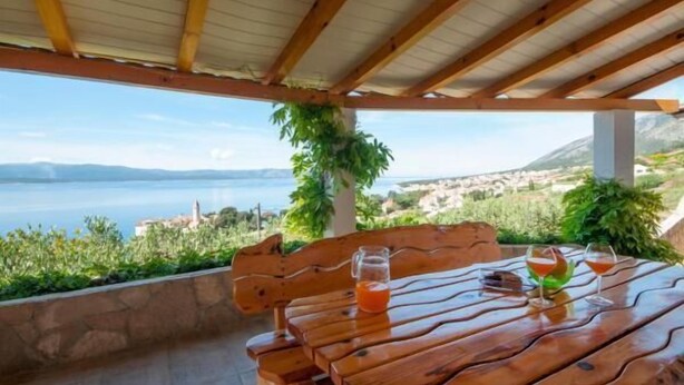Una mesa de madera con vistas al mar y a las montañas.