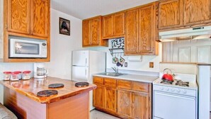 A compact kitchen with wooden cabinets, a microwave, a refrigerator, a sink, and a stove. - Scenic Wonders Alpine View 2 Bedroom (Yosemite National Park)