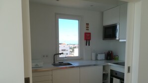 A compact kitchen with a window, white cabinets, a microwave, and a toaster.