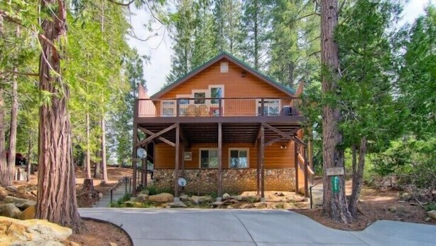 A two-story cabin with a balcony, surrounded by trees. - Scenic Wonders  Bear Den 5 Bedrooms (Yosemite National Park)