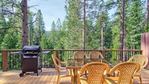 A deck with a grill, wicker chairs, and a glass table. - Scenic Wonders  Bear Den 5 Bedrooms (Yosemite National Park)