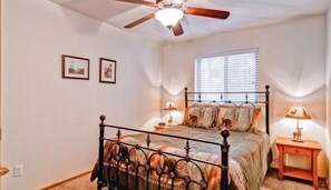 A bedroom with a bed, a ceiling fan, a window with blinds, and two framed pictures on the wall. - Scenic Wonders  Bear Den 5 Bedrooms (Yosemite National Park)
