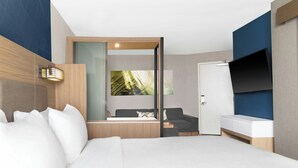 A modern hotel room with a large bed, a sofa, a desk, and a TV. - SpringHill Suites by Marriott Holland (Holland)