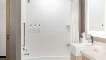 Un baño moderno con ducha a nivel, bañera y tocador con lavamanos.