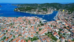 An aerial view of a coastal town with densely packed buildings, a marina, and a hilly backdrop. - Apartments Sunshine Home - Twin Room (Blue) (Vela Luka)