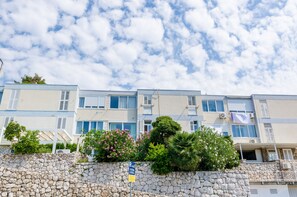 A multi-story building with a stone wall, a parking sign, and a clear sky. - Apartment Petrana - Studio Apartment with Terrace (Dubrovnik)