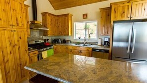 A kitchen with wooden cabinets, a stainless steel refrigerator, a stove, and a microwave. - Scenic Wonders Birds Eye Vista 3 Bedroom (Yosemite National Park)