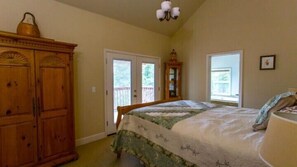 A bedroom with a bed, wooden wardrobe, and a door leading outside. - Scenic Wonders Birds Eye Vista 3 Bedroom (Yosemite National Park)