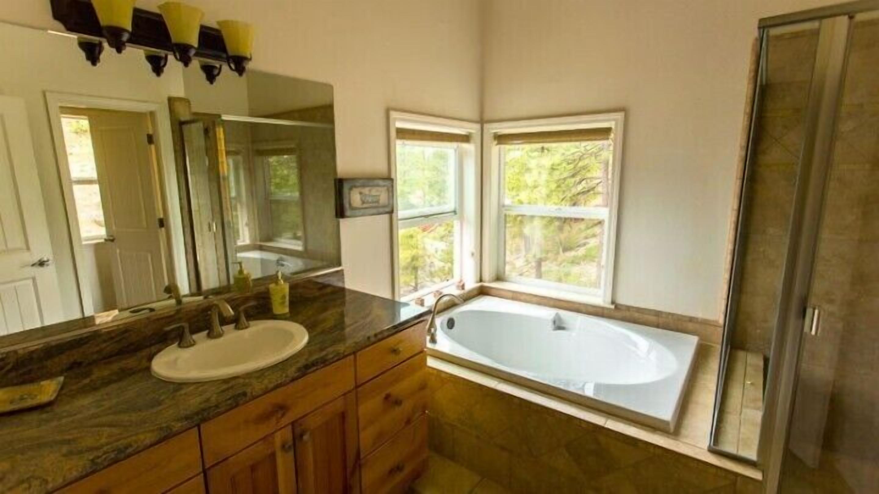 A bathroom with a large bathtub, a double sink vanity, and a shower.