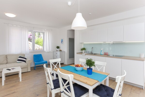 A modern kitchen with white cabinets, a wooden countertop, and a blue tablecloth.