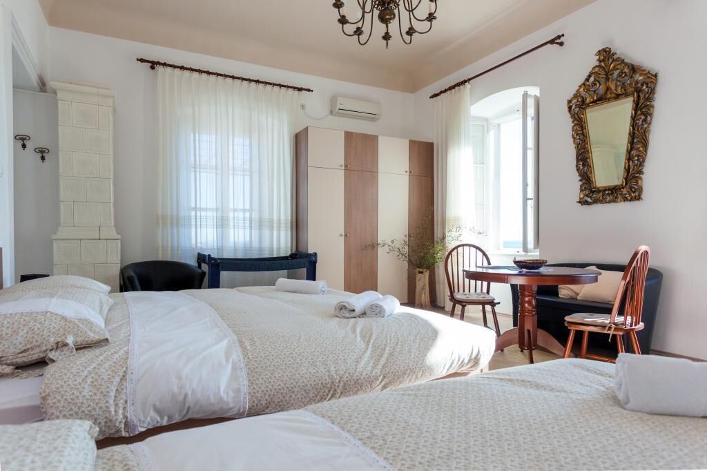 Una camera d'albergo con due letti, una scrivania, una sedia, uno specchio e una pianta in vaso.