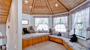 Ett mysigt rum med en inbyggd bänk längs fönstret, träbjälkar i taket och en nallebjörn på bänken.