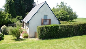 A small white building with a sloped roof, a wooden door, and a window with a wooden frame. - Charming house in a quiet (Guengat)