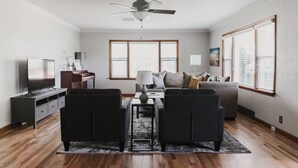 Ein Wohnzimmer mit Deckenventilator, Fernseher, Sofa und Couchtisch.