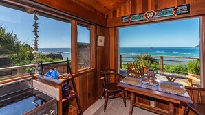 Un interior de fusta amb vista a l'oceà, una taula de dinar amb caires i una zona de cuina.