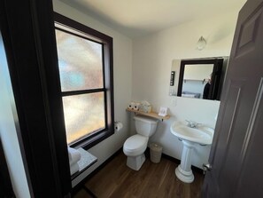 Ein kleines Badezimmer mit Toilette, Waschbecken und Fenster.