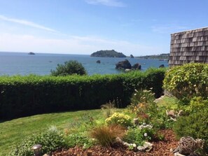 Un jardin aménagé offrant une vue sur la mer et les formations rocheuses.