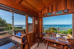 Un intérieur en bois avec vue sur l’océan, une table à manger avec des chaises et un coin cuisine.
