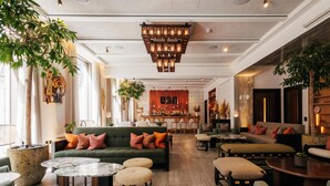 A spacious lobby with a green sofa, round tables, and a bar area. - Hart Shoreditch Hotel London, Curio Collection by Hilton (London)