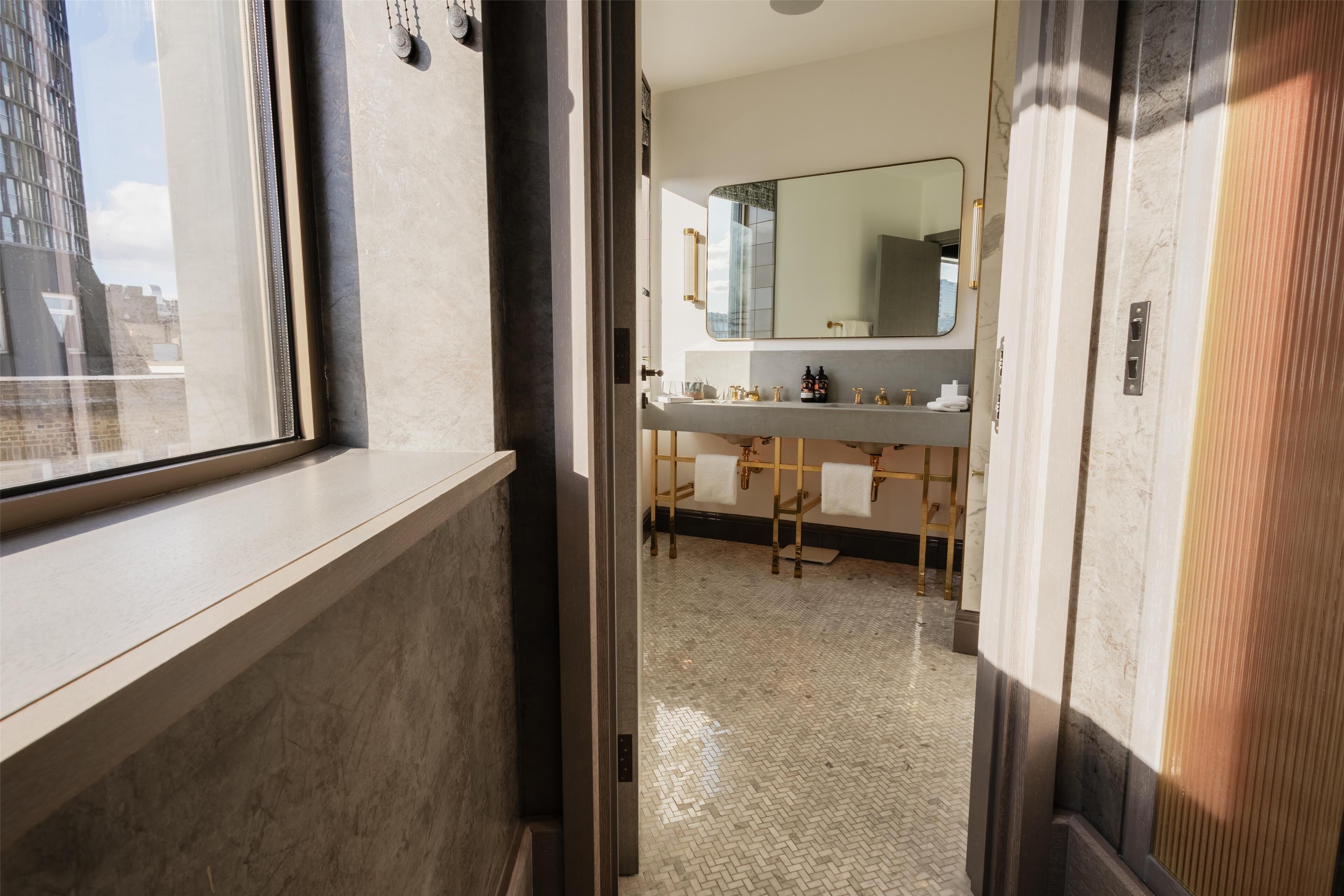 A modern bathroom with a large mirror, a sink, and a towel rack.