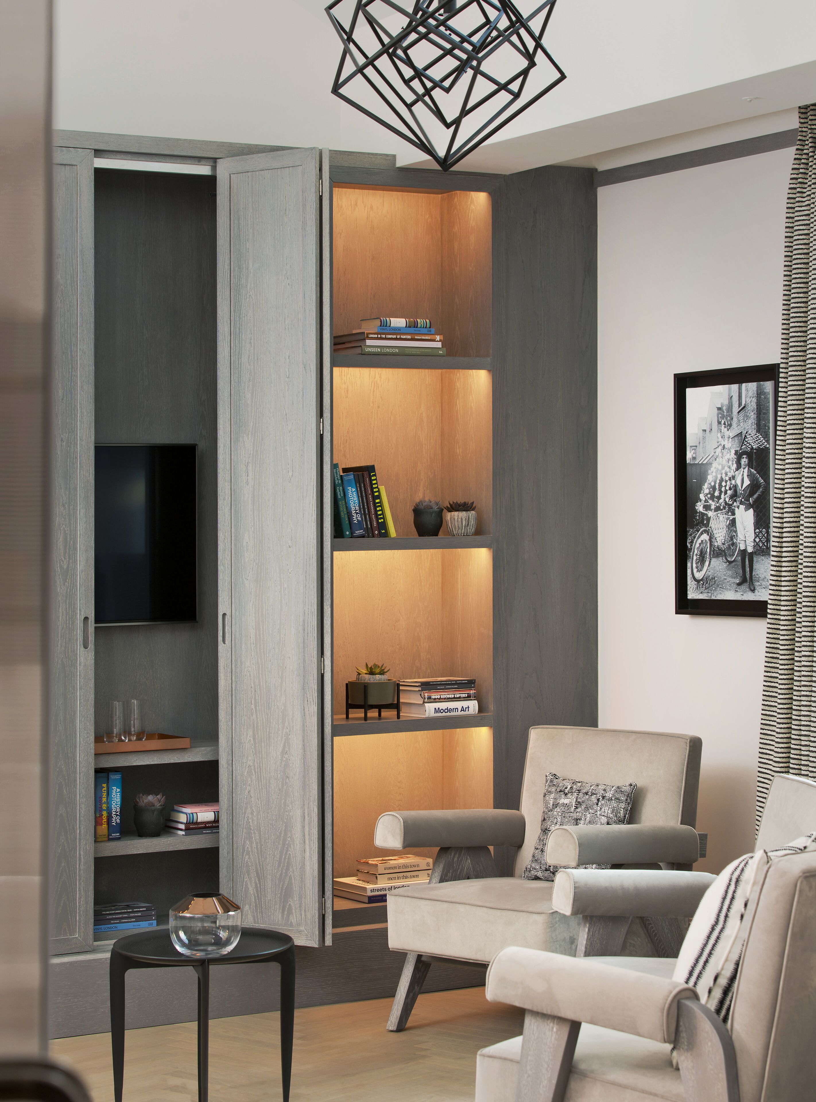 A modern living room with a grey sectional sofa, a black coffee table, and a bookshelf with books and decorative items.