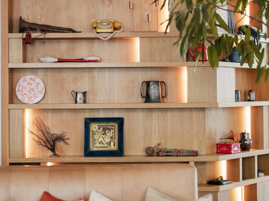 Una estantería de madera con diversos objetos decorativos y un sofá con cojines.