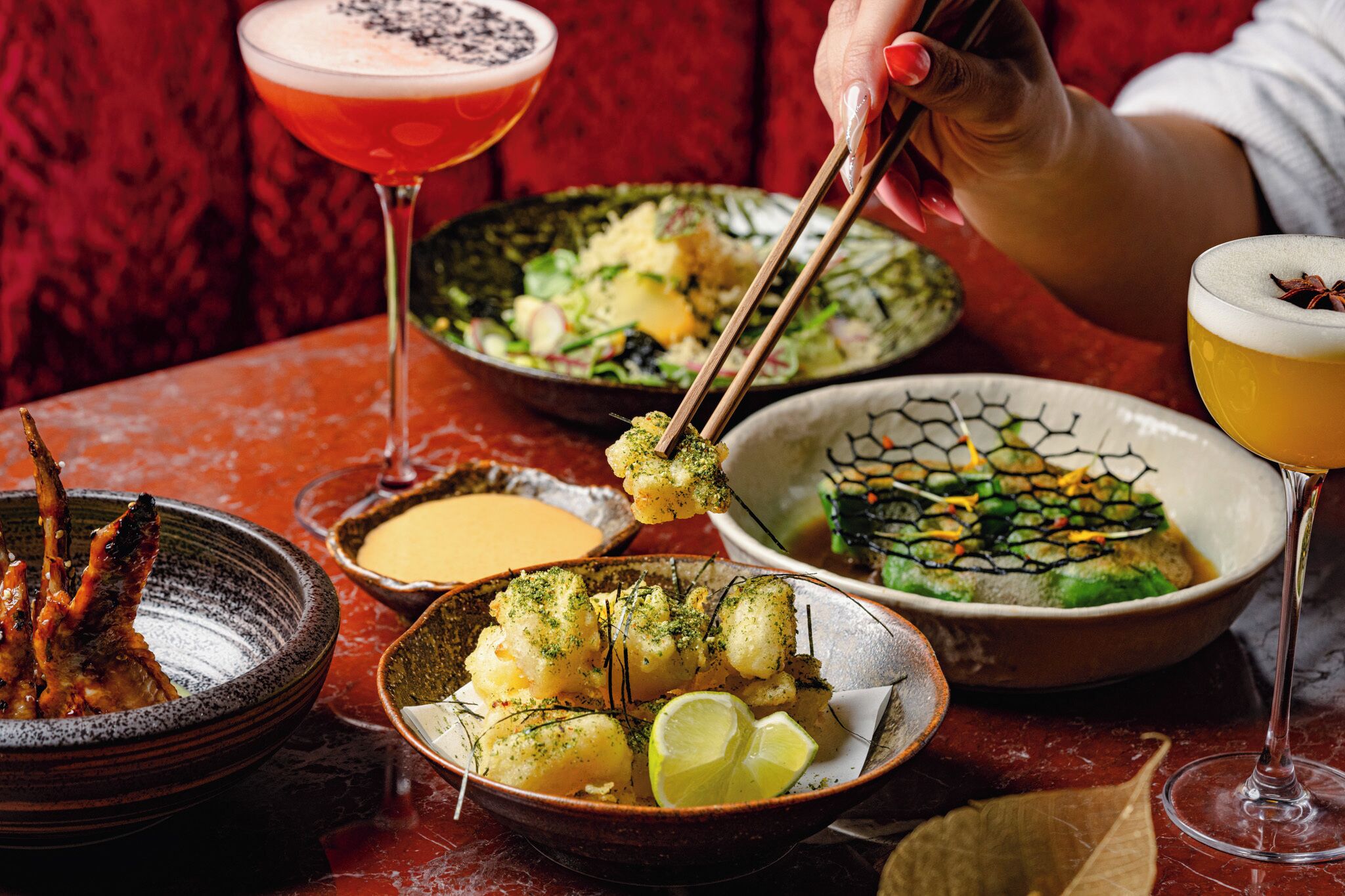 Uma mesa com diversos pratos, incluindo frutos do mar e legumes, e duas bebidas.